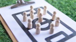 Football tactical clipboard on top of green football field.