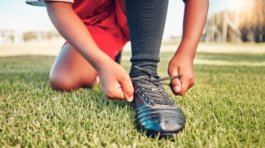 Sports, football field and child tie shoes for match workout, challenge contest or practice exercis